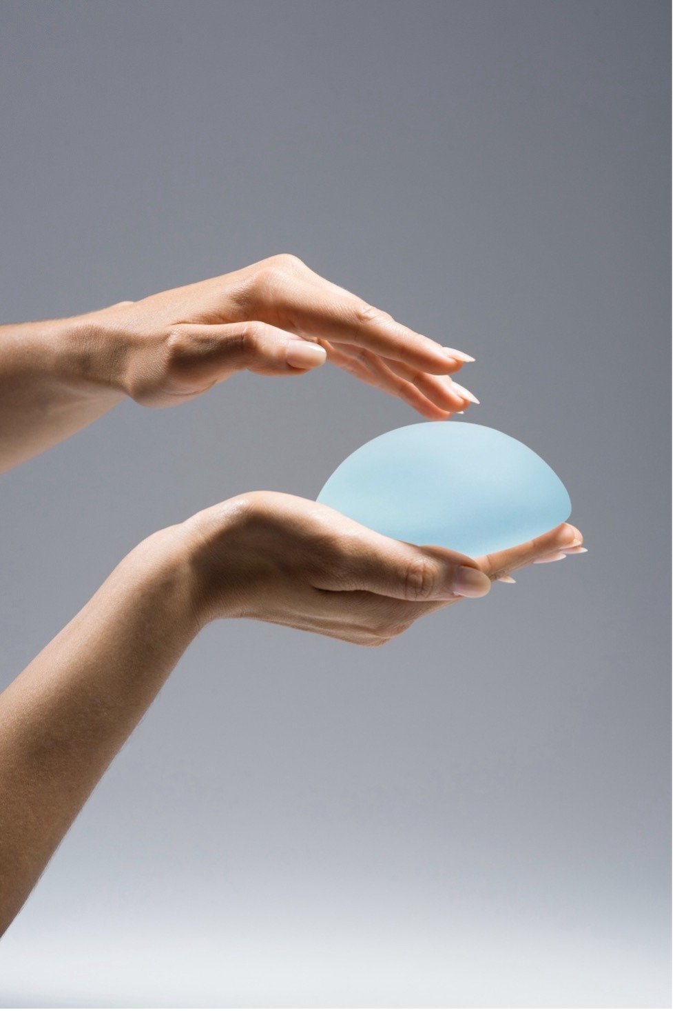 woman holding motiva breast implant in hand